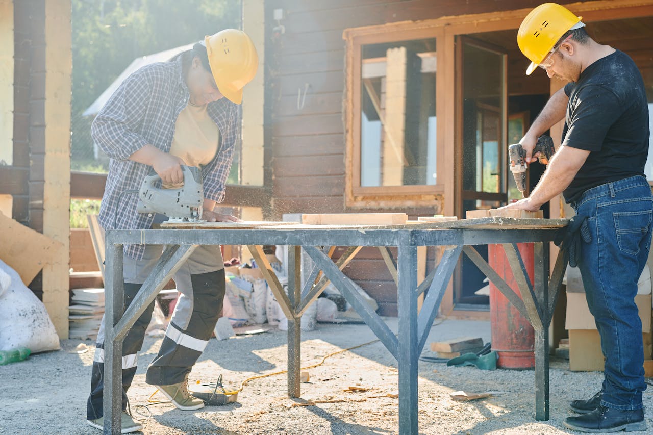 Man and Woman in Yellow Hard Hats Working Using Industrial Tools